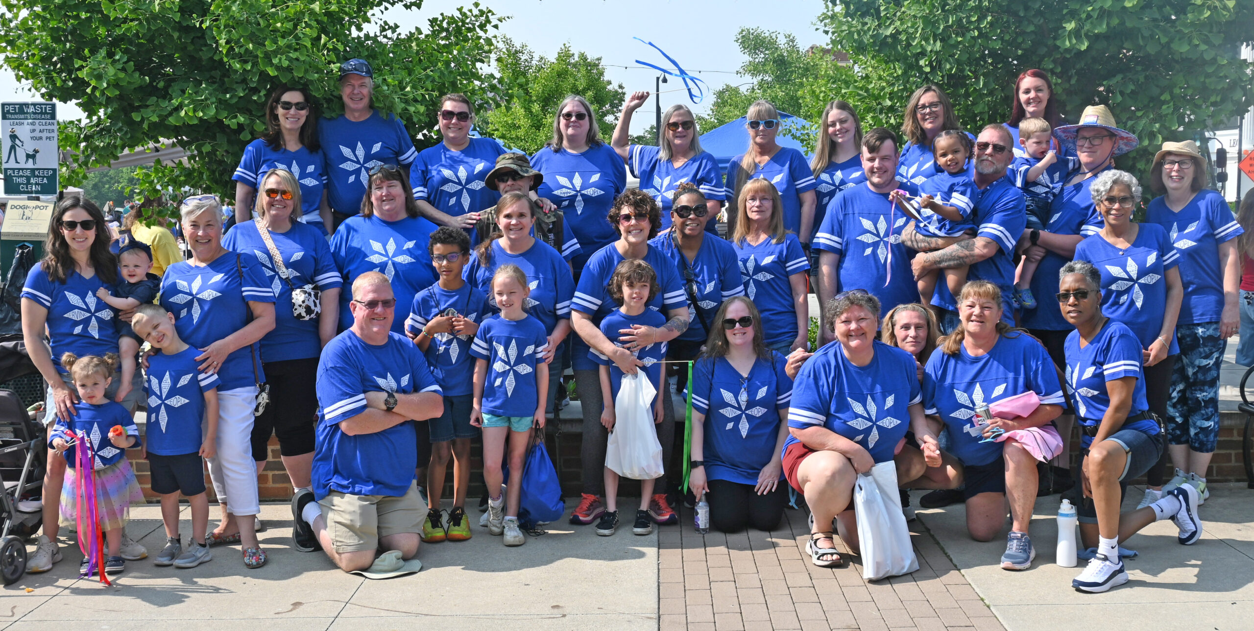 This is a group picture of smiling UDS employees in matching blue t-shirts with the UDS logo on it. They are at the 2025 Autism Walk in Akron.