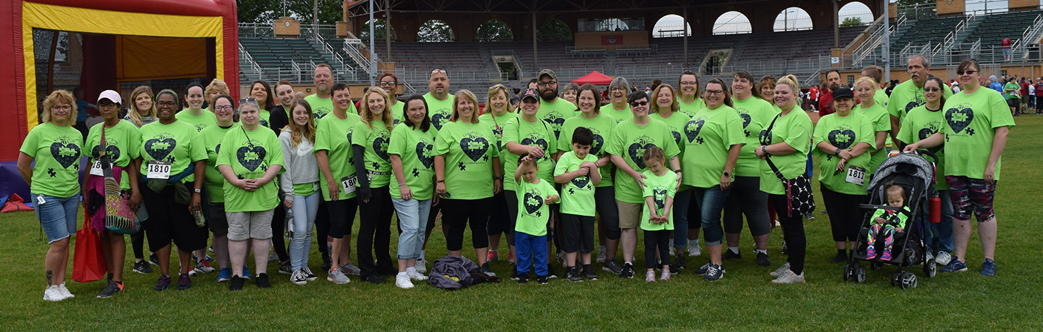 A large group of UDS participants attend an autism walk. They wear matching neon green t-shirts.